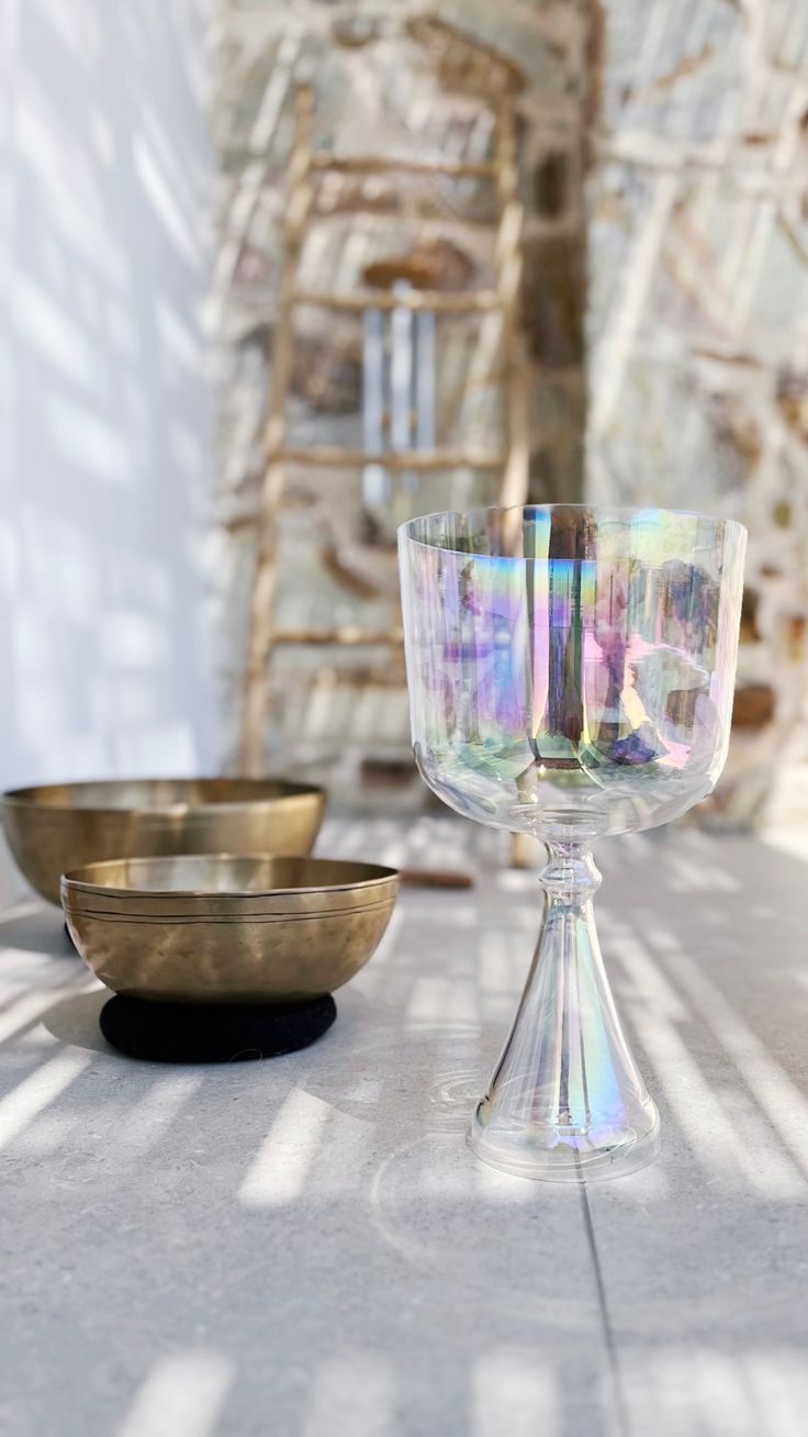 Crystal vs Tibetan singing bowl comparison — clear crystal chalice beside two Tibetan metal bowls
